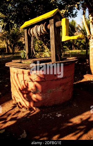 Colorful retro well of water with rope placed at a farm in the countryside Stock Photo