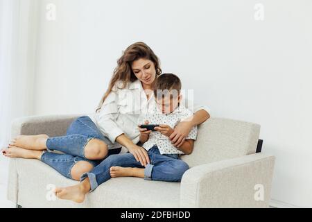 Mom and son play smartphone games on the couch Stock Photo