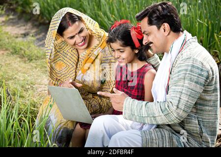 Rural family using laptop on agriculture field Stock Photo