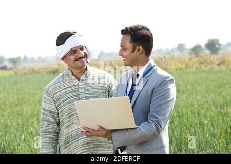 Businessman discussing with farmer using laptop on agricultural field Stock Photo