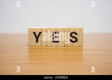 Wooden block on desk with the word Yes. Stock Photo