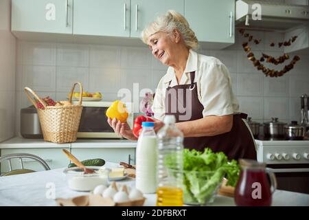 Charming old woman cooking dinner in kitchen at home Stock Photo