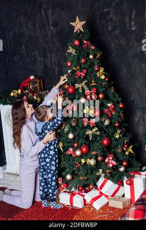 Mom and boy decorates Christmas tree Christmas New Year Stock Photo