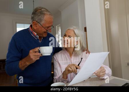 Happy senior caucasian couple with coffee cup calculating finances at home Stock Photo