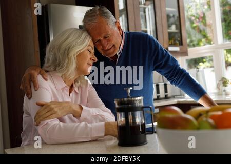 Senior caucasian couple embracing each other in the kitchen at home Stock Photo