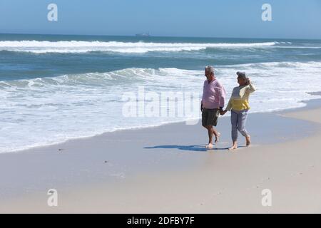 Senior caucasian couple walking on beach holding hands by sea Stock Photo