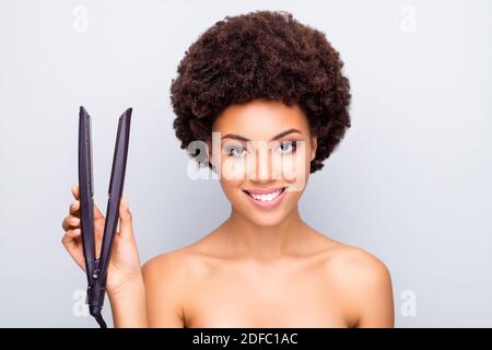 Close-up portrait of her she nice attractive cheerful cheery confident wavy-haired girl holding in hands iron straightener device isolated on light Stock Photo