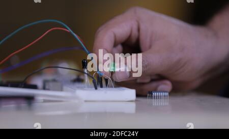 Electronic components connecting in Breadboard, a hand of technician holds led light Stock Photo