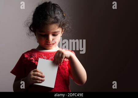 Little girl opening a small box in front of body, editable mock-up series template ready for your design, box faces selection path included. Stock Photo