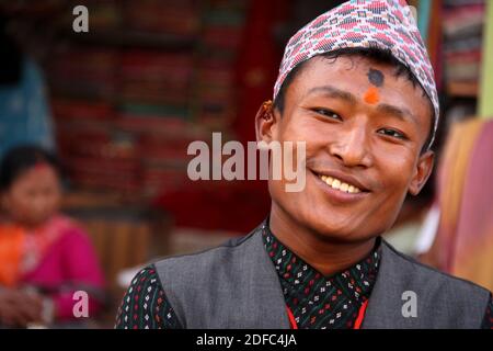 Nepal, in Patan, young Nepalese man smiling with tilak and traditional hat called Dhaka topi Stock Photo