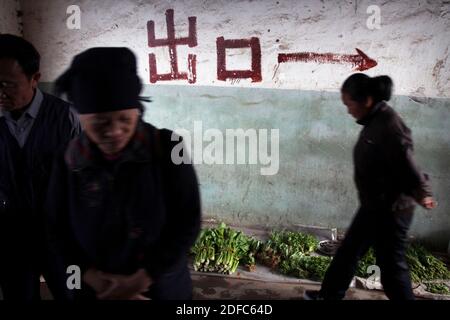 China, Yuanyang, women at Yuanyang market with arrow painted on a wall to show the direction Stock Photo
