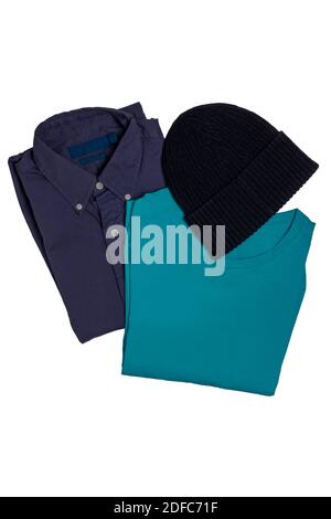 Hipster man's clothing isolated. Closeup of a folded stylish violet shirt, a blue t-shirt and a black cap or hood isolated on a white background. Mens Stock Photo