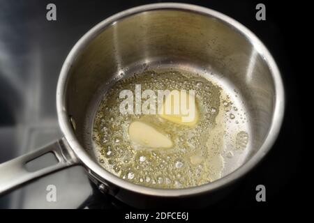 Melting butter in a stainless steel saucepan on the black stove, cooking concept, selected focus, narrow depth of field Stock Photo