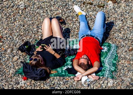 Two People Relaxing On One of The Riverside ‘Beaches’ , River Thames, London, UK. Stock Photo