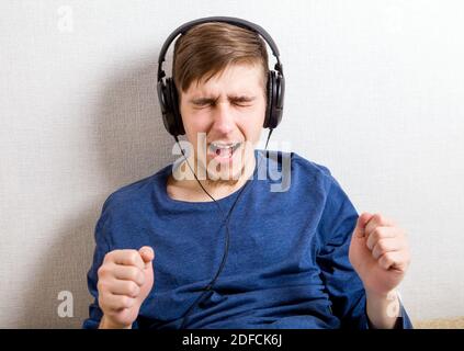 Happy Young Man in the Headphones listen to the Music by the Wall Stock Photo