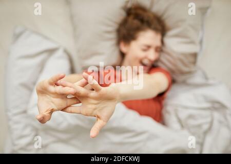 Young happy woman waking up in the morning she stretching while lying in bed Stock Photo