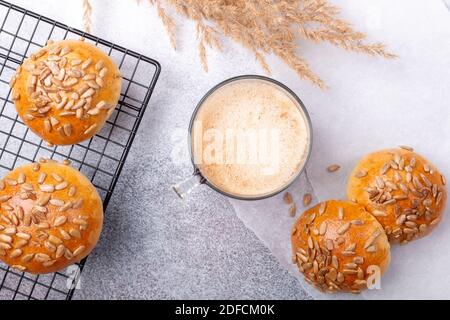 Coffee and fresh homemade bread rolls with seeds on cooling rack. Breakfast with coffee and pastries. Top view - Image Stock Photo