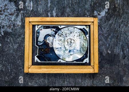 Crushed Hard Disk Drive in the Frame on the Old Wooden Background closeup Stock Photo