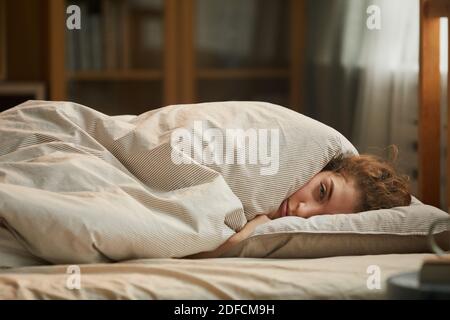 Portrait of young woman lying under the blanket in her bed she feeling herself bad Stock Photo