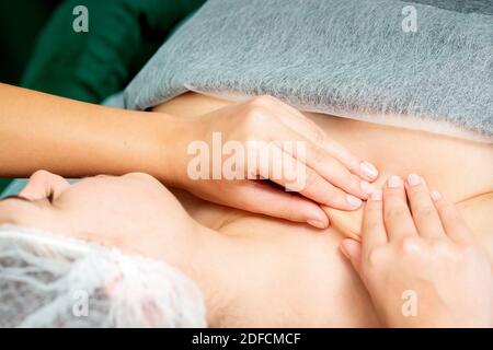 Closeup of young woman receiving neckline and chest massage by