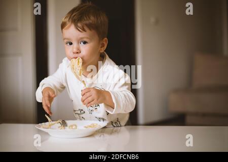 Cute little boy, eating spaghetti at home for lunchtime Stock Photo