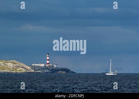 A sailboat motoring past Eilean Glas Lighthouse on a summer day Stock Photo