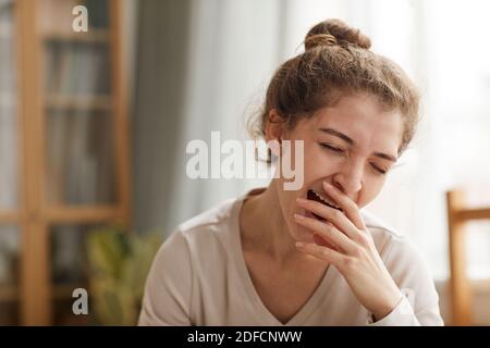 Young woman yawning sitting at home she tired after work Stock Photo