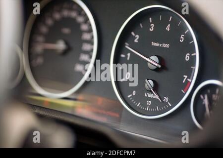 Rev counter of car selective focus closeup with copyspace. Tachometer or revolution counter, RPM gauge with red glowing needle on car dashboard with Stock Photo