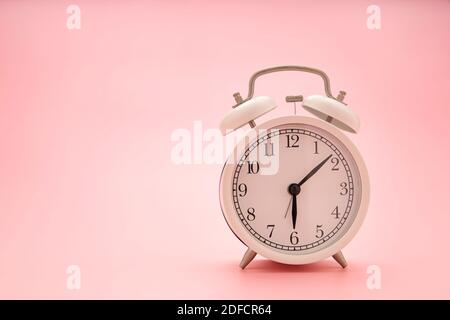 Close up a white clock on a pink background. Concept image. Stock Photo