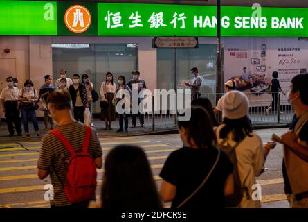 Pedestrians wait to cross the street in front of a Hang Seng Bank branch in Hong Kong. Stock Photo