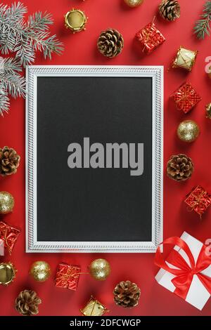 Photo frame with free black space around Christmas decorations and gifts on a red background. Top view, free space for text Stock Photo