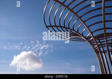 Conceptual abstract sculpture of metal chrome pipes against deep blue sky. Stock Photo