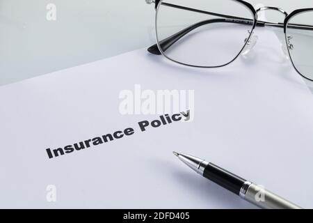 A closeup shot of an insurance policy document with pen and glasses on it Stock Photo