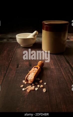 Himalayan pink salt crystals in a wooden scoop on wooden worktop, Stock Photo