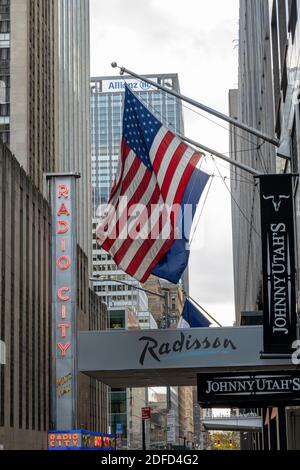 American flag on West 51st Street with Radio City Musical Hall in the background, Rockefeller Center, New York City, USA Stock Photo