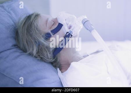 Treatment of sleep apnea and snoring : patient suffering from Obstructive Sleep Apnea Syndrome (OSAS) connected to a continuous positive airway pressu Stock Photo