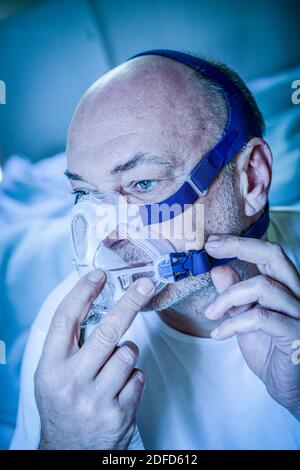 Treatment of sleep apnea and snoring : patient suffering from Obstructive Sleep Apnea Syndrome (OSAS) connected to a continuous positive airway pressu Stock Photo