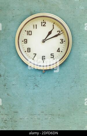 Vintage mid twentieth century plastic electric clock on a blue weathered wall Stock Photo