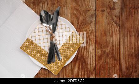 Place setting for dinner on rustic background. Christmas table setting with gold decorations on wooden table. Top view. Copy space. Stock Photo