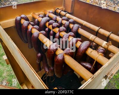 Home made sausages hanging in wooden smoker outdoor Stock Photo