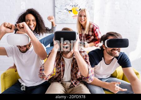 KYIV, UKRAINE - OCTOBER 19, 2020: excited multicultural friends using vr headsets near woman holding joystick on blurred background Stock Photo