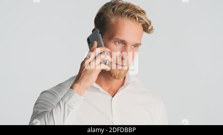 Handsome bearded man in shirt talking with business partner on smartphone over white background. Business talk. Modern technology Stock Photo