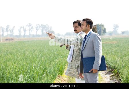 Businessman discussing with farmer on agriculture field Stock Photo