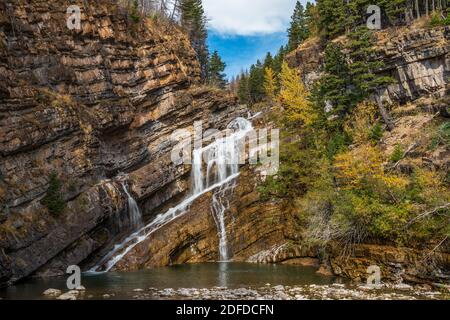 Cameron falls in autumn sunny day morning. Blue sky, white clouds over mountains in the background. Waterton Lakes National Park, Alberta, Canada. Stock Photo