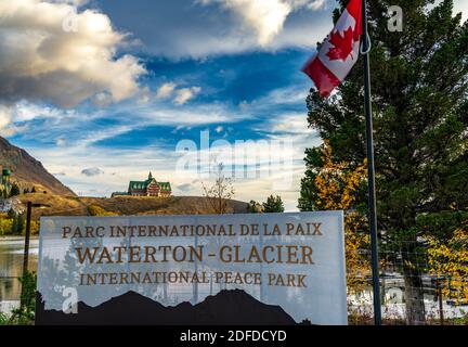 Waterton-Glacier International Peace Park in autumn foliage season. Waterton lake shore at dawn, beautiful fiery clouds in sunrise time. Waterton Lake Stock Photo