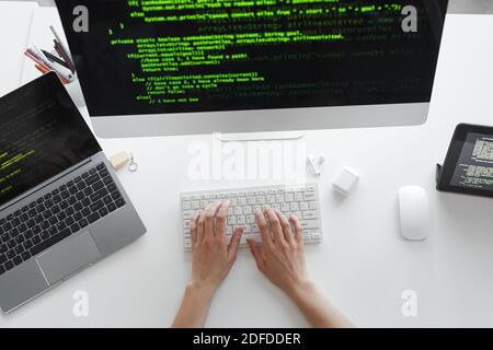 High angle view of developer typing on computer keyboard installing the new system on computer at the table Stock Photo