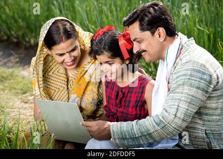 Rural family using laptop on agriculture field Stock Photo