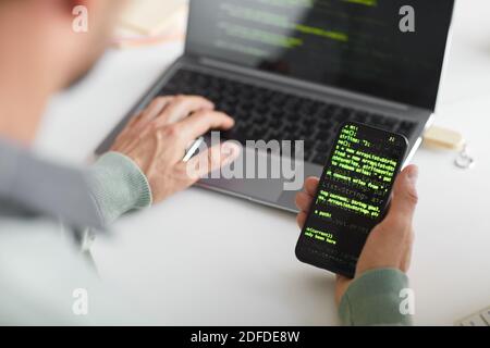 Close-up of man installing new software system on his mobile phone from laptop Stock Photo