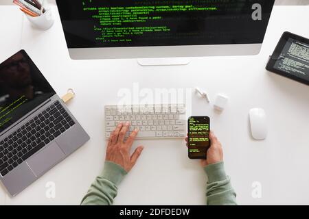 High angle view of programmer sitting at the table using computer laptop and mobile phone programming website design Stock Photo