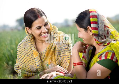 Two happy indian rural women talking on agricultural field Stock Photo